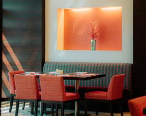 a dining room with a table and chairs and a vase of flowers at Doha Central Plaza Hotel in Doha
