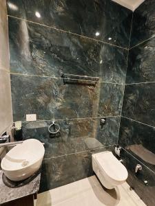 a bathroom with a toilet and a black tiled wall at Hotel Cloud 9 in Amritsar