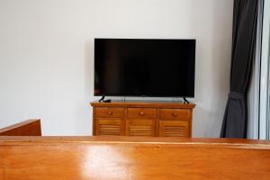 a flat screen tv sitting on top of a wooden dresser at Coasta Wings Hostel in Nathon Bay +8 photos
