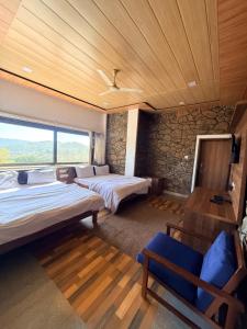 a bedroom with two beds and a stone wall at Dev Cottage in Mount Ābu