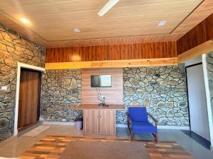 a stone wall with a blue chair in a room at Dev Cottage in Mount Ābu