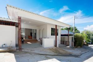 a white house with a courtyard in front of it at Coasta Wings Hostel in Nathon Bay