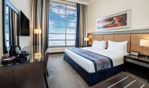 a hotel room with a bed and a desk and a window at Doha Central Plaza Hotel in Doha
