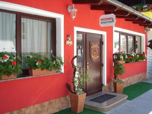 Un edificio rojo con plantas en macetas y una puerta. en Penzion Gostilna Keber, en Domžale