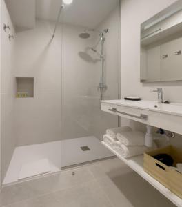 a white bathroom with a shower and a sink at 6 de Mayo alojamientos in Almansa