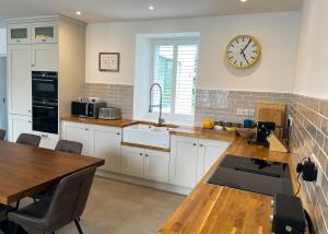a kitchen with a table and a clock on the wall at Willow in Clifden +12 photos
