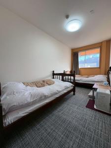 a bedroom with two beds and a window at 駅本ビル民宿4階 in Yuzawa