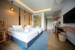 ein Hotelzimmer mit zwei Betten und einem Flachbildfernseher in der Unterkunft The Blue Mavi Hotel in Chalong  + 57 Fotos