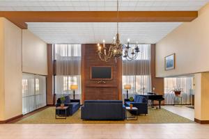 a lobby with couches and a television and a piano at MainStay Suites Lansing West in Lansing