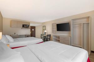 a hotel room with two beds and a flat screen tv at MainStay Suites Lansing West in Lansing
