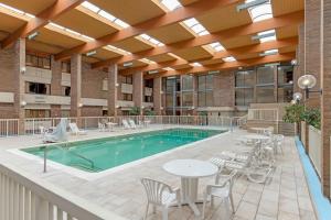 a pool with chairs and a table in a building at MainStay Suites Lansing West in Lansing