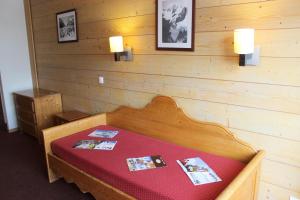 een bed in een kamer met een houten wand bij Temples Du Soleil Tikal Appartements VTI in Val Thorens