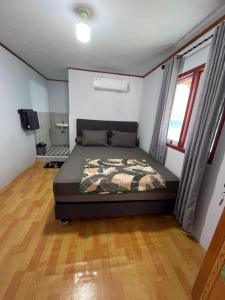 a bedroom with a bed in a room with wooden floors at Homestay Natasya in Pohe
