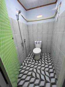 a bathroom with a toilet and a black and white tiled floor at Homestay Natasya in Pohe