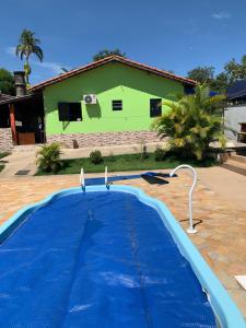a blue swimming pool in front of a green building at Recanto Pedrita in Pedreira