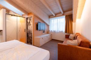 a bedroom with a bed and a couch and a tv at Guest House Fleim in Panchià