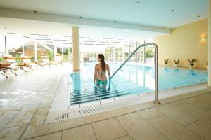 a woman is standing in a swimming pool at Wander- & Wellnesshotel Nägele in Höchenschwand