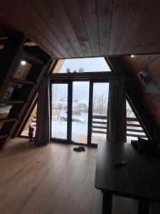 an attic room with a large window and a table at Aurora Cottage Tabatskuri Lake in Tabatsquri
