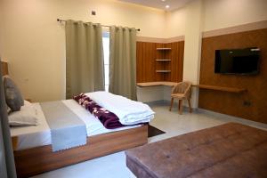 a bedroom with a bed and a tv and a chair at Hotel Highway Nest in Chamba
