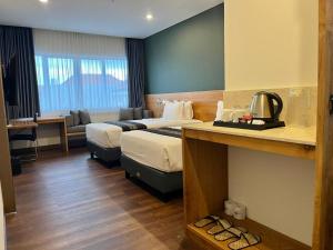 a hotel room with two beds and a couch at Griya Pastoral in Denpasar