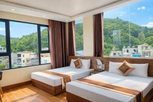 two beds in a room with a large window at Ngọc Tùng Hotel in Ha Long