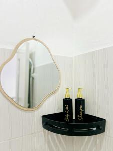 a black shelf with two candles in front of a mirror at Mars Homestay Ubud in Ubud +2 photos