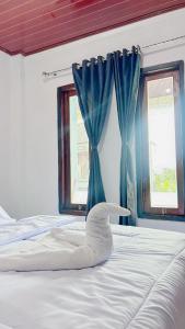 a bedroom with a bed with blue curtains and a whale made out of towels at Mars Homestay Ubud in Ubud