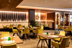 a restaurant with wooden tables and yellow chairs at Hotel Hell in Ortisei +92 photos