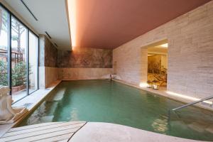 a swimming pool in a house with a large window at La Posta Hotel & Thermal Spa - Adults Only in Bagno Vignoni