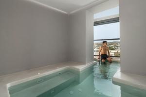 a man standing in the water in a swimming pool at Uncle's House Junior Suite INDOOR Pool in Adamantas
