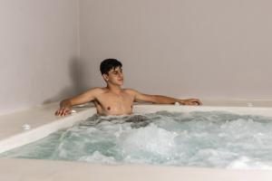 a man is sitting in a bath tub at Uncle's House Junior Suite INDOOR Pool in Adamantas +23 photos