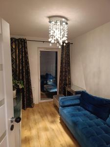 a living room with a blue couch and a chandelier at Perła Residence in Kutno +2 photos