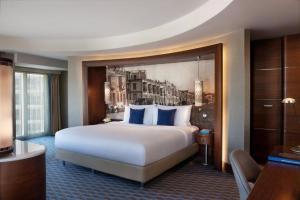 a hotel room with a large bed with blue pillows at Renaissance Izmir Hotel in İzmir