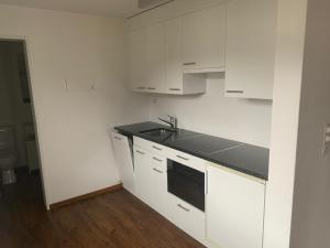 a kitchen with white cabinets and a black counter top at Satin Home in Savognin