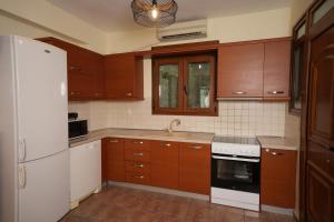 a kitchen with wooden cabinets and a white refrigerator at Golden Beach, Gerakini in Gerakini