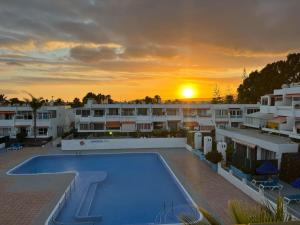 a sunset over a building with a swimming pool at Pandora apartment in Las Galletas