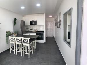 a kitchen with white cabinets and a table and chairs at Pandora apartment in Las Galletas