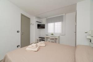 a white bedroom with a bed with towels on it at Domo Le Mura Puniche, nel cuore di Olbia in Olbia