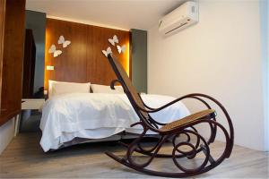 a chair in front of a bed in a room at Chung Fu Inn in Tainan