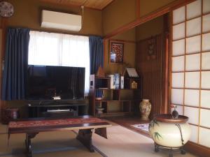 a living room with a tv and a table and a window at ゲストハウス有無 in Mihama