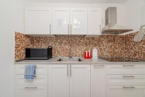 a white kitchen with a sink and a microwave at Domo Le Mura Puniche, nel cuore di Olbia in Olbia