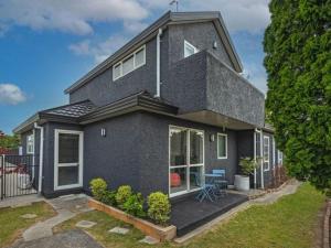 a blue house with a porch and a table in front of it at City centred living! in Palmerston North