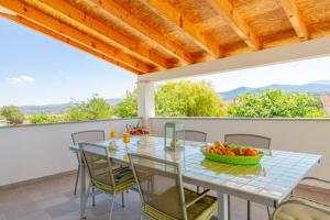 a table with chairs and a bowl of fruit on a patio at Holiday house Anetta with 5 bedrooms in Imotski