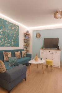 a living room with a blue couch and a tv at Colorful House Tsoutsouras in Tsoutsouros
