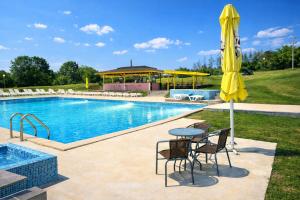 a pool with a table and a yellow umbrella at Комплекс Кремена in Kremena