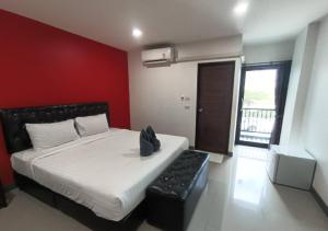 a bedroom with a large bed with a red wall at เคทูกรีน สุพรรณบุรี in Ban Hua Phrong