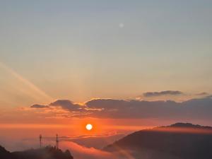 a sunset over a mountain with the sun in the sky at Mandira Homestay in Jālāpahār