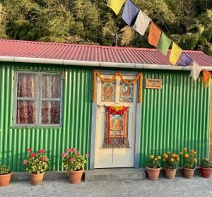 a green building with pots of flowers and flags at Mandira Homestay in Jālāpahār