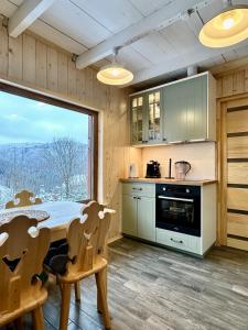 a kitchen with a table and chairs and a large window at Pod Srebrzystym Świerkiem - Jacuzzi in Koszarawa +47 photos