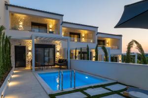 a villa with a swimming pool in front of a house at Kara Villas in Kallithea Halkidikis